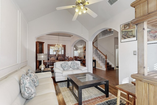 living room with dark wood-type flooring, ceiling fan with notable chandelier, and high vaulted ceiling