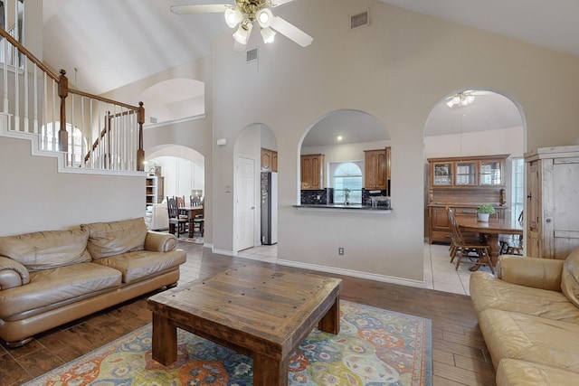 living room featuring ceiling fan, high vaulted ceiling, and light hardwood / wood-style flooring