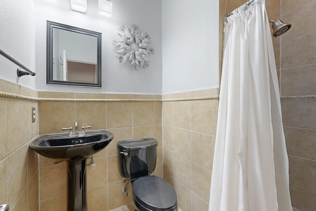 bathroom featuring tile walls, sink, a shower with curtain, and toilet