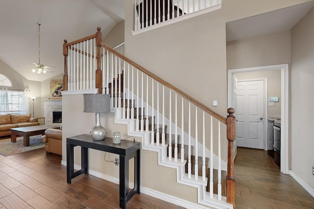 staircase with wood-type flooring, a fireplace, and high vaulted ceiling