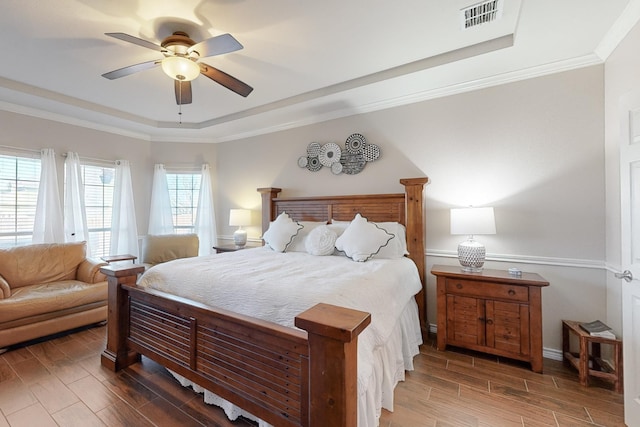 bedroom with a raised ceiling, crown molding, and ceiling fan