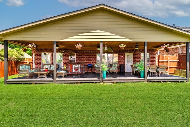 back of property with a wooden deck, ceiling fan, and a lawn