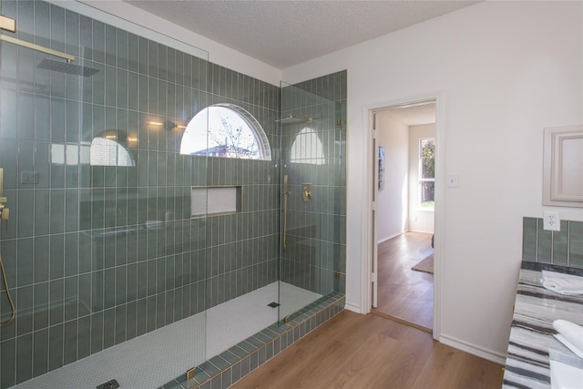 bathroom with a tile shower, hardwood / wood-style floors, and a textured ceiling