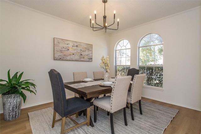 dining space featuring crown molding, wood-type flooring, and a notable chandelier