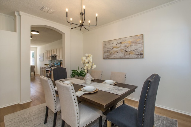 dining area with dark hardwood / wood-style flooring, crown molding, a textured ceiling, and an inviting chandelier