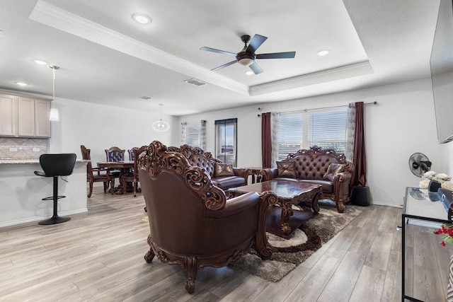 living room featuring crown molding, a tray ceiling, light hardwood / wood-style flooring, and ceiling fan