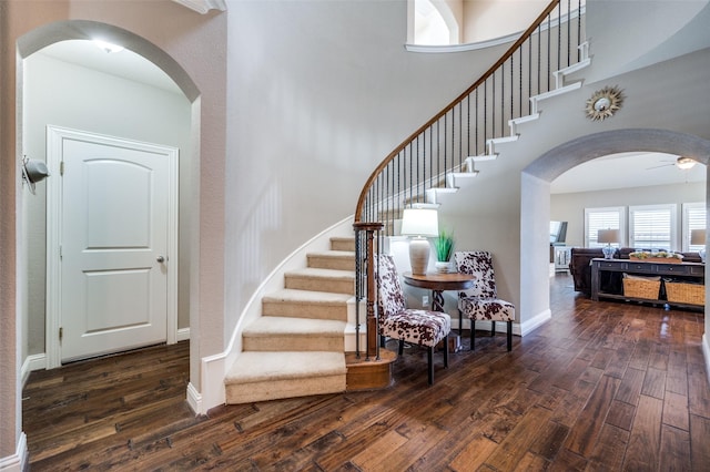 entryway with ceiling fan, dark hardwood / wood-style floors, and a high ceiling