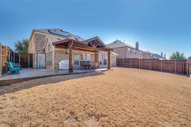 rear view of property featuring a patio area, brick siding, a yard, and a fenced backyard