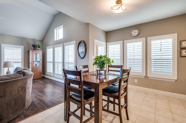 tiled dining space with baseboards and vaulted ceiling