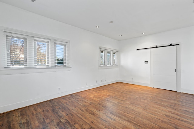 unfurnished room with hardwood / wood-style floors, a wealth of natural light, and a barn door