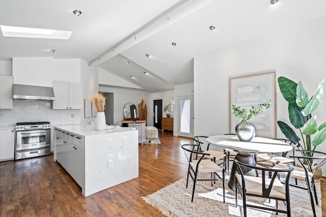 kitchen with dark wood-type flooring, stainless steel gas range oven, white cabinetry, vaulted ceiling with skylight, and wall chimney range hood