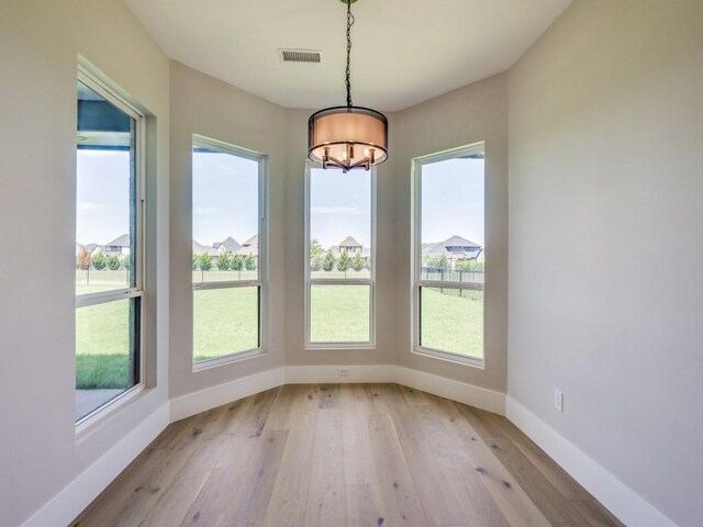 1165 Stonebridge Pass, Gunter, TX 75058 - unfurnished dining area with a chandelier, light wood-type flooring, and baseboards