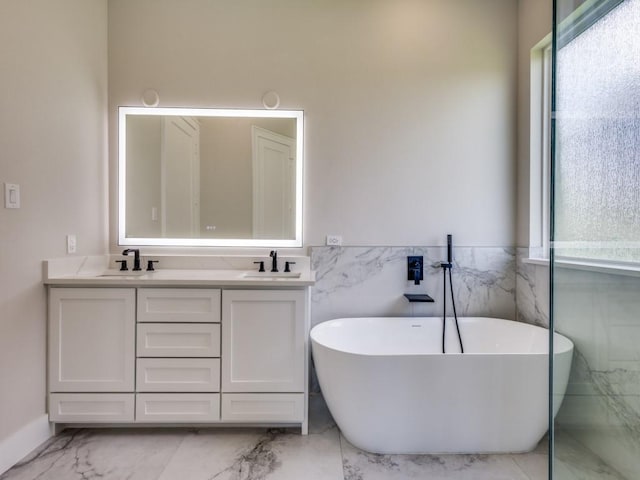 1165 Stonebridge Pass, Gunter, TX 75058 - bathroom with marble finish floors, double vanity, a freestanding bath, tile walls, and a wainscoted wall