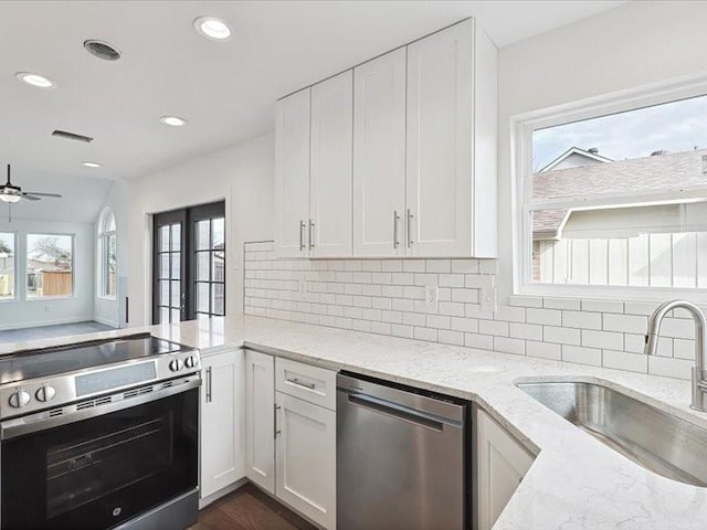 kitchen featuring sink, white cabinetry, stainless steel appliances, tasteful backsplash, and light stone countertops