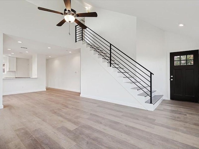 entrance foyer with ceiling fan, high vaulted ceiling, and light hardwood / wood-style flooring