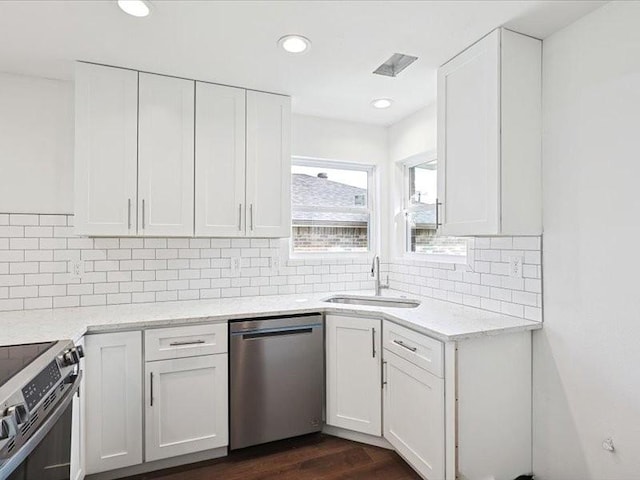 kitchen featuring sink, white cabinets, dark hardwood / wood-style flooring, decorative backsplash, and stainless steel appliances