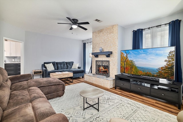 living room with a fireplace, wood-type flooring, and ceiling fan