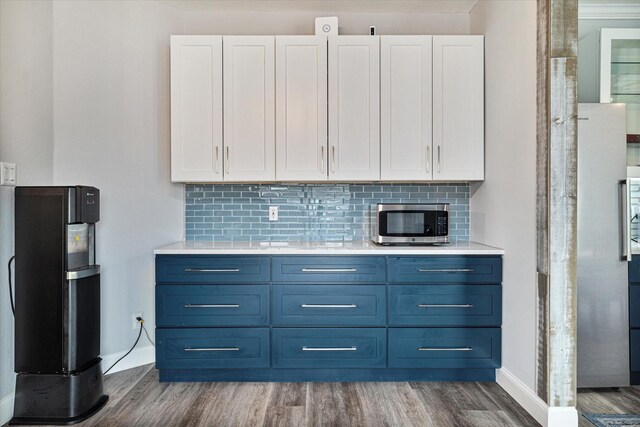 kitchen with white cabinetry, blue cabinetry, dark wood-type flooring, and backsplash