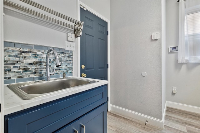 kitchen featuring tasteful backsplash, sink, blue cabinetry, and light hardwood / wood-style flooring