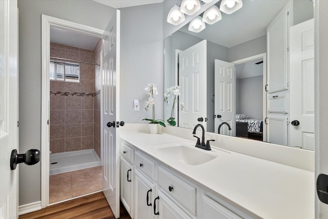 bathroom featuring hardwood / wood-style flooring, vanity, and a tile shower