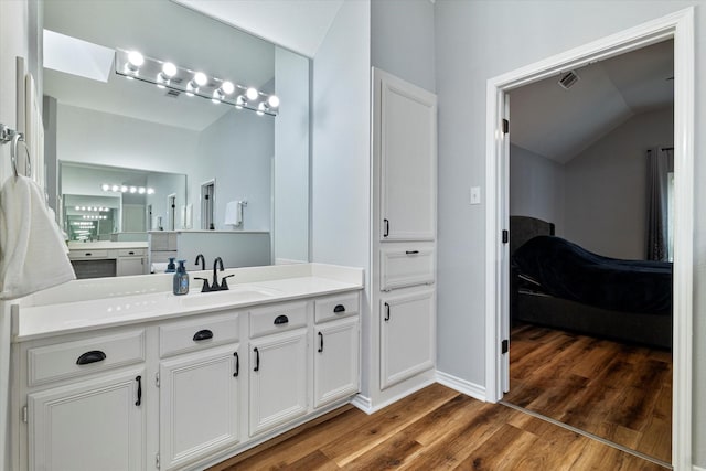 bathroom with wood-type flooring, vaulted ceiling, and vanity