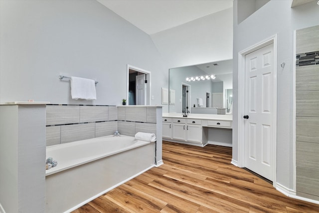 bathroom featuring vanity, a tub to relax in, hardwood / wood-style floors, and lofted ceiling