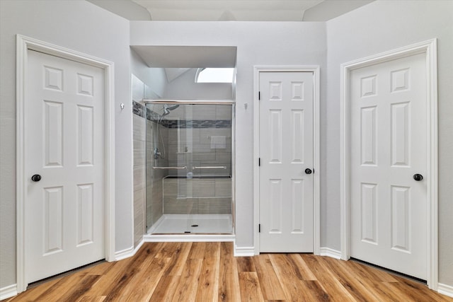 bathroom with hardwood / wood-style flooring and a shower with shower door