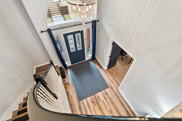 entrance foyer featuring an inviting chandelier, a towering ceiling, and wood-type flooring