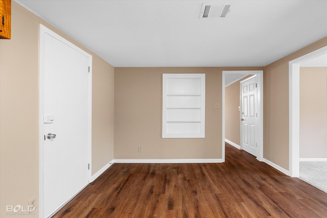 unfurnished room with dark hardwood / wood-style flooring and built in shelves