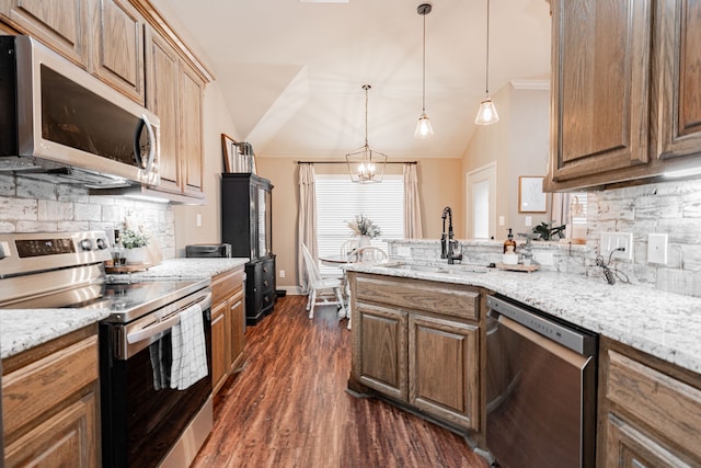 kitchen with lofted ceiling, sink, hanging light fixtures, stainless steel appliances, and light stone countertops