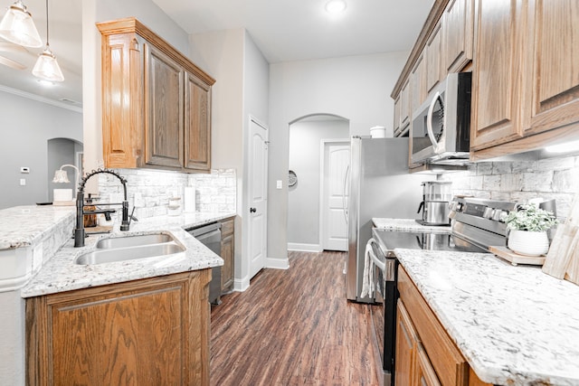 kitchen featuring appliances with stainless steel finishes, sink, backsplash, dark hardwood / wood-style flooring, and hanging light fixtures