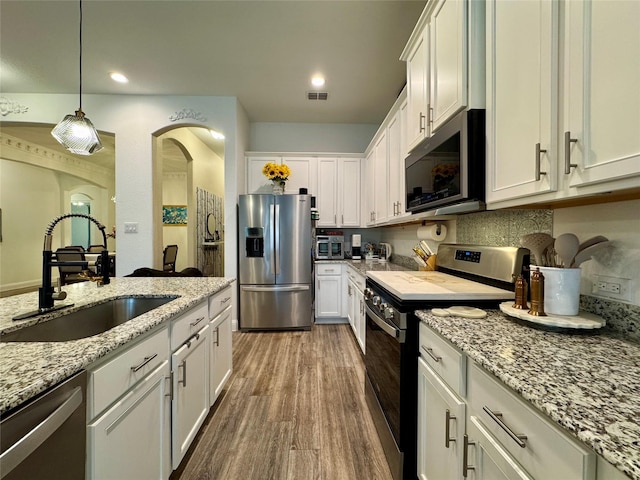 kitchen featuring sink, stainless steel appliances, hanging light fixtures, and white cabinets