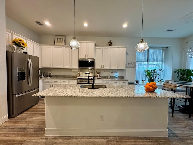 kitchen featuring white cabinetry, stainless steel appliances, and a center island with sink