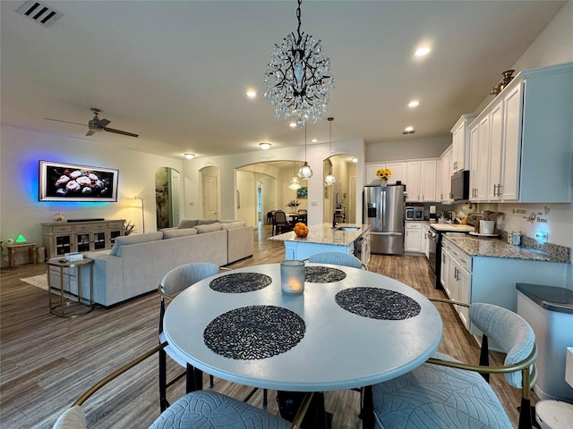 dining room featuring sink, dark hardwood / wood-style floors, and ceiling fan with notable chandelier