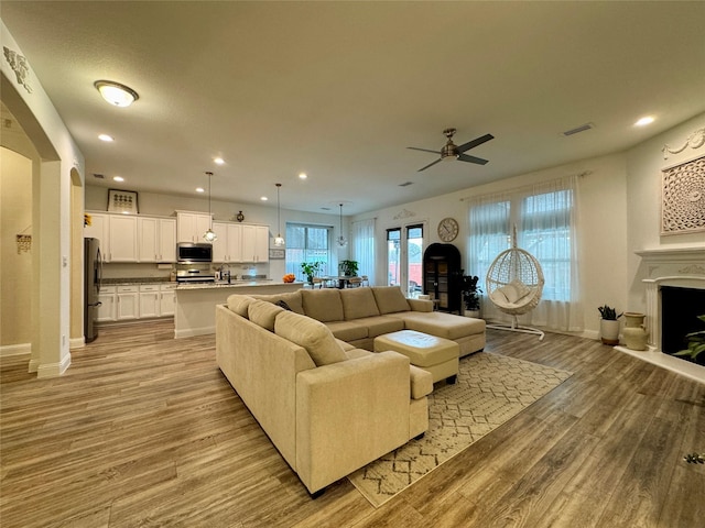 living room featuring ceiling fan, sink, and light hardwood / wood-style floors