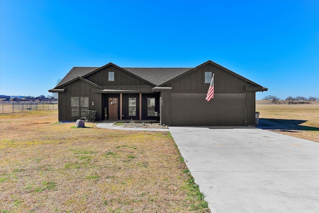 view of front of home with a garage, a front lawn, and a rural view