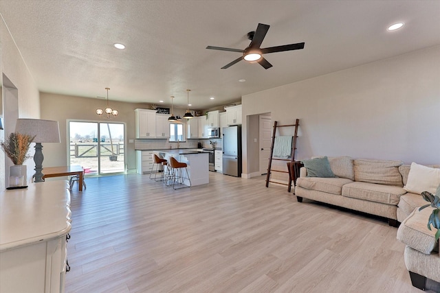 living room featuring ceiling fan, a textured ceiling, and light hardwood / wood-style floors