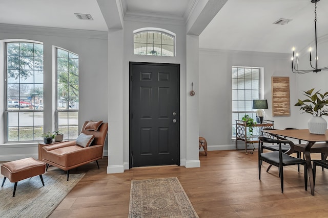 entrance foyer with crown molding, an inviting chandelier, and light hardwood / wood-style floors