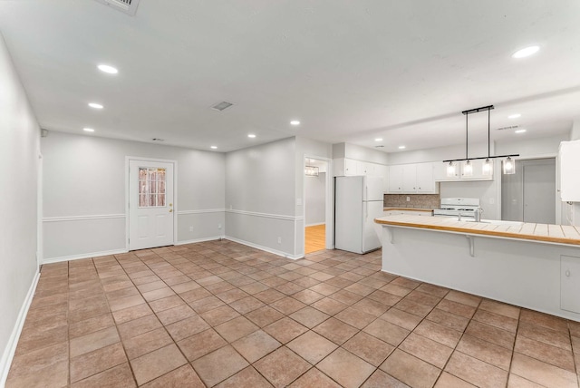 kitchen with pendant lighting, white appliances, a breakfast bar area, tile counters, and white cabinets