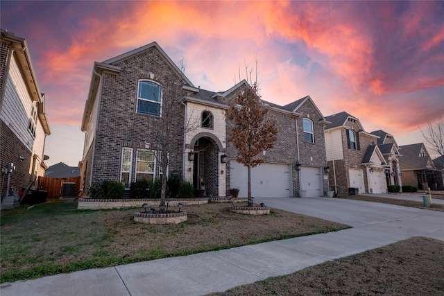 traditional home with brick siding, a lawn, an attached garage, fence, and driveway