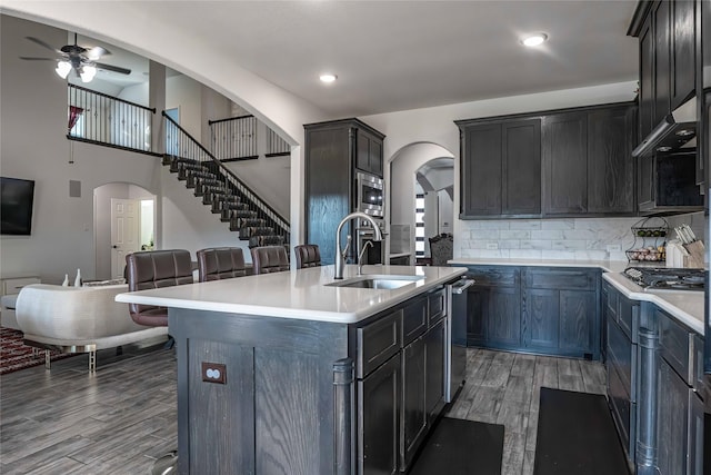 kitchen with arched walkways, stainless steel appliances, a sink, and open floor plan