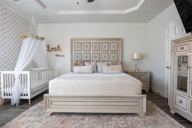 bedroom with baseboards, crown molding, a tray ceiling, and dark wood-type flooring