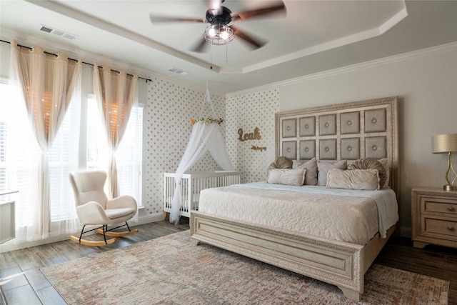 bedroom featuring multiple windows, a raised ceiling, and wood finished floors