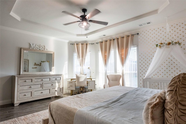 bedroom with visible vents, baseboards, ornamental molding, dark wood-style floors, and a tray ceiling