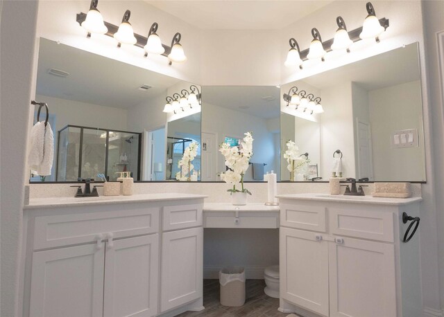 bathroom featuring visible vents, toilet, a shower stall, vanity, and wood finished floors