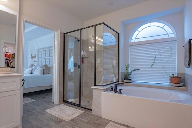 ensuite bathroom featuring a garden tub, a shower stall, connected bathroom, and wood finished floors