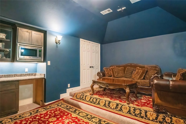 interior space featuring baseboards, visible vents, light colored carpet, lofted ceiling, and built in study area