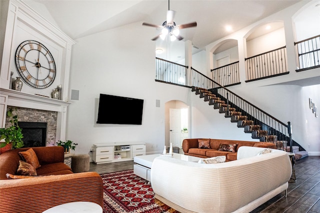 living area with arched walkways, dark wood finished floors, stairway, a fireplace, and high vaulted ceiling