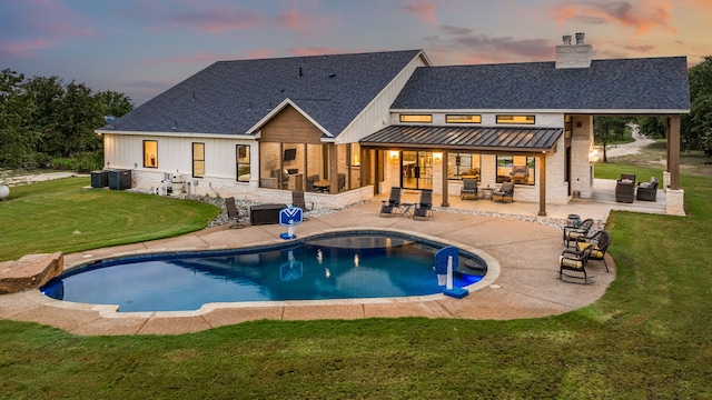 back house at dusk with a patio, a yard, and central air condition unit