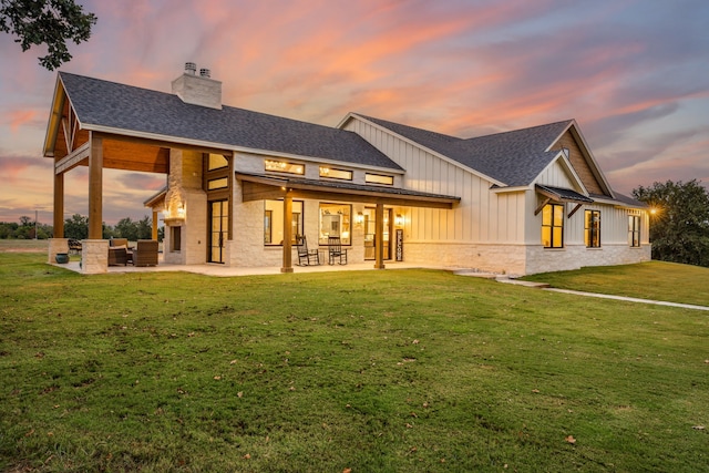 back house at dusk featuring a yard and a patio area